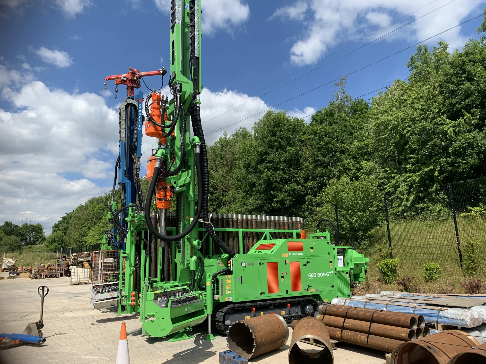 Drilling rig set up beside woodland beneath a blue sky